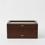 The TAWBURY Bayswater 24 Slot Watch Box with Drawer in chestnut brown features a glass top, metal handles, and "TAWBURY" embossed on the front—ideal for watch storage. Shown against a plain white background.