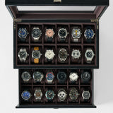 The TAWBURY Bayswater 24 Slot Watch Box with Drawer in Black/Charcoal holds up to 24 wristwatches, neatly organized in slots, offering stylish storage for various watch bands and face designs.