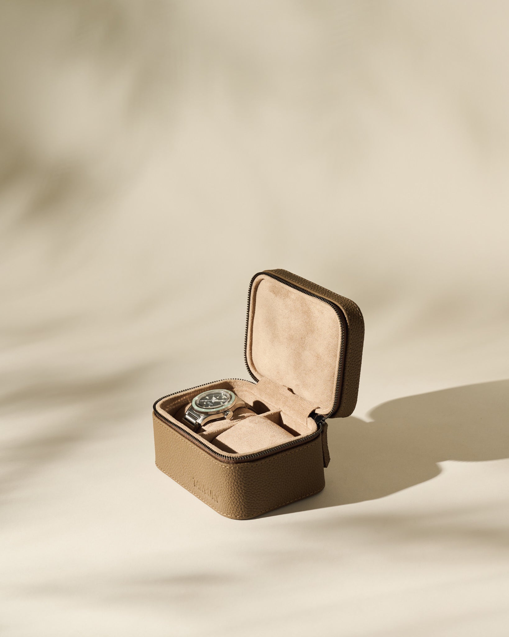 The Fraser 2 Watch Case - Taupe by TAWBURY, crafted in brown textured leather with a beige suede interior, is photographed on a neutral, softly lit background.