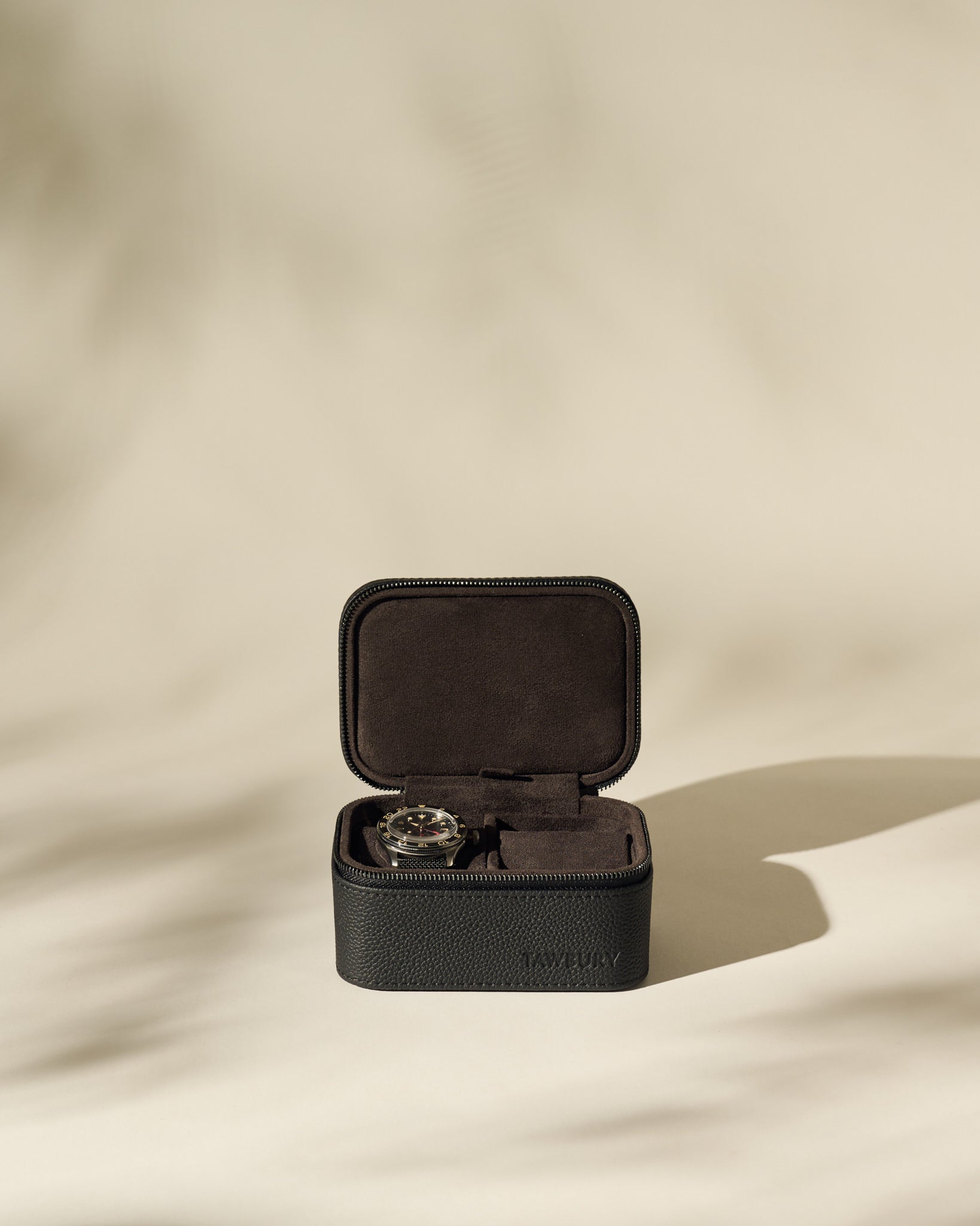 The TAWBURY Fraser 2 Watch Case - Black sits open on a neutral surface, displaying a wristwatch inside against a soft beige background—ideal as a stylish travel case for your timepieces.