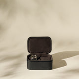 The TAWBURY Fraser 2 Watch Case - Black sits open on a neutral surface, displaying a wristwatch inside against a soft beige background—ideal as a stylish travel case for your timepieces.