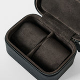 The TAWBURY Fraser 2 Watch Case - Black is a compact, rectangular leather travel case with a black zip exterior and soft brown divided interior, designed to securely store and protect two watches or jewelry on the go.