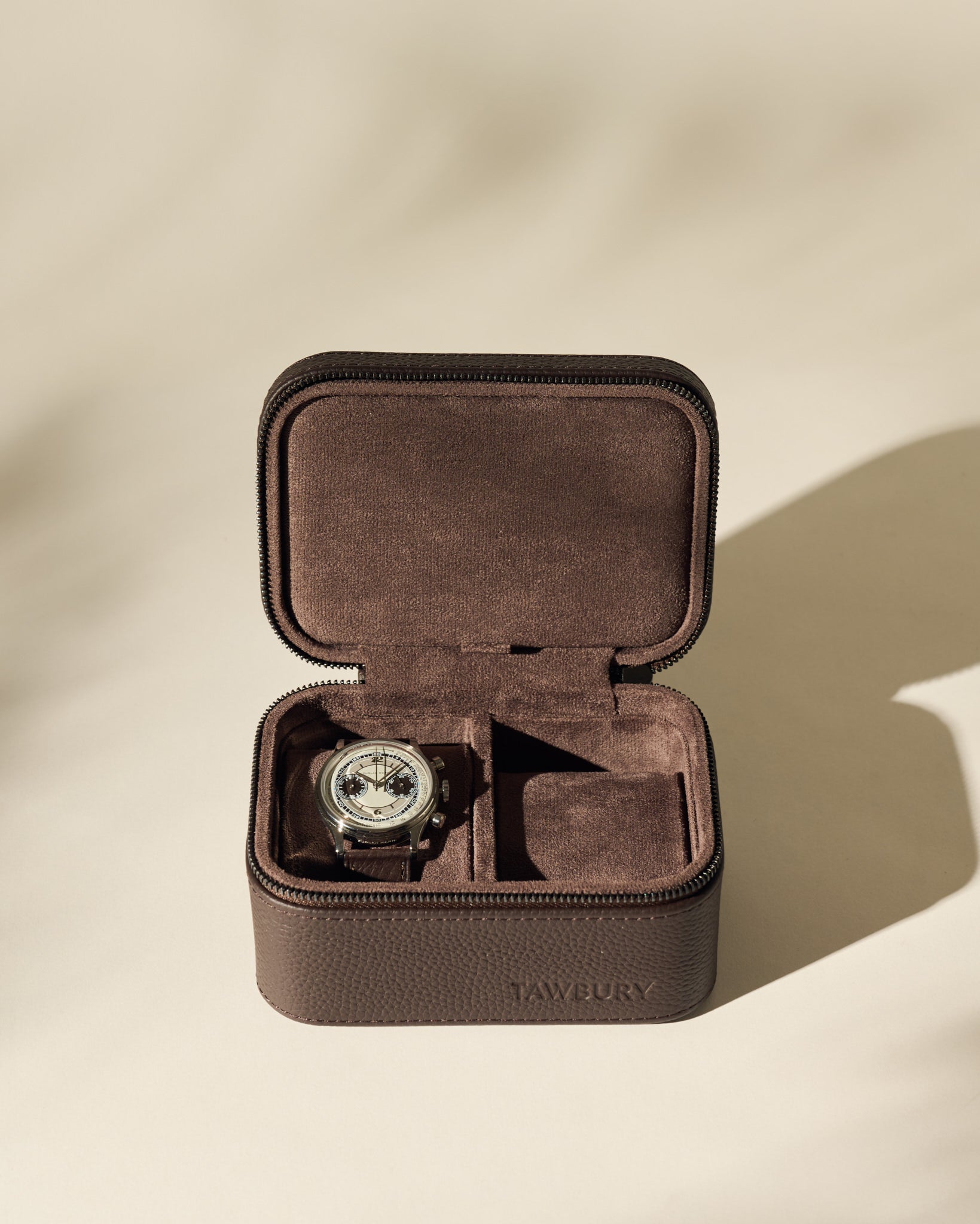 A wristwatch is displayed inside an open TAWBURY Fraser 2 Watch Case - Brown, with a second empty compartment.