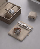 Displayed on a gray surface are TAWBURY Fraser Collection accessories: two watches, a brown leather band, a metal bracelet, and the Fraser 3 Watch Travel Case with Storage in Taupe—a chic and multifunctional leather watch travel case.