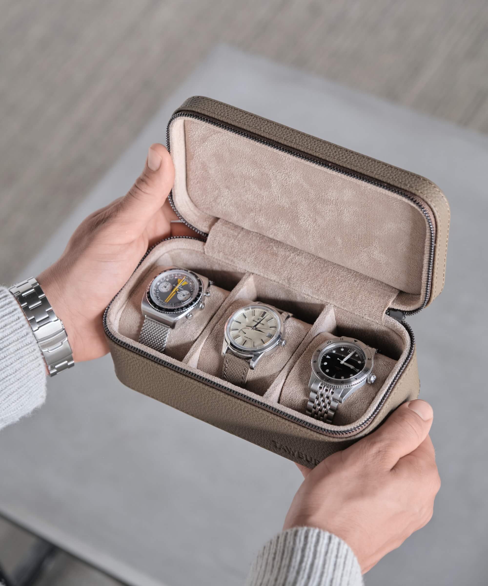 A person showcasing a TAWBURY Fraser 3 Watch Travel Case - Taupe with three watches securely protected within its compact design.