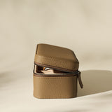 The TAWBURY Fraser 3 Watch Case in taupe textured leather, featuring a zippered closure, rests partially open on a softly lit, neutral background.