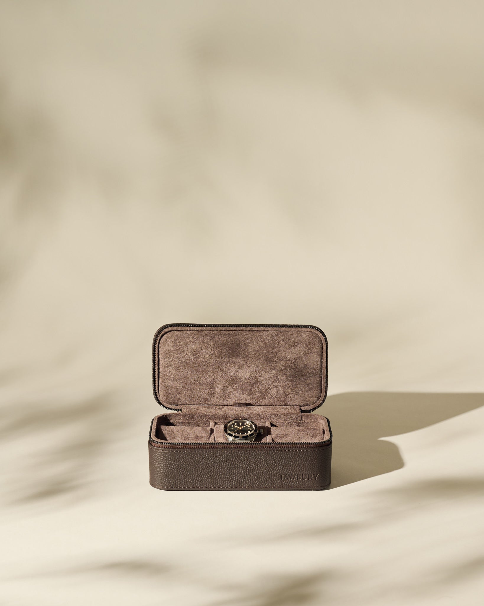 The TAWBURY Fraser 3 Watch Case in brown leather sits open, displaying a wristwatch inside—ideal for travel storage—against a neutral backdrop with gentle shadows.