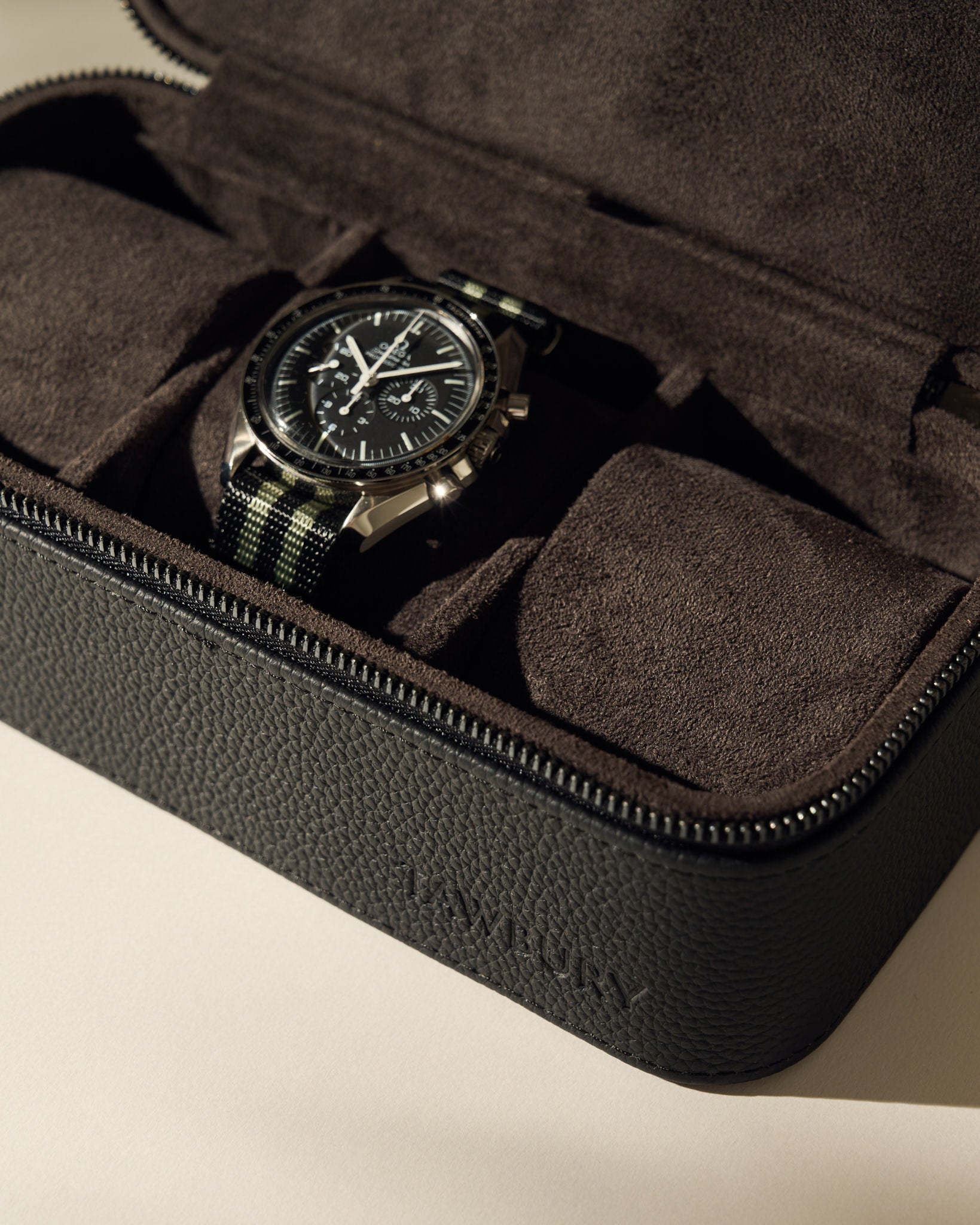 The TAWBURY Fraser 3 Watch Case - Black is a sleek black textured leather case with a zipper and suede interior, ideal for stylishly storing your watches on the go.