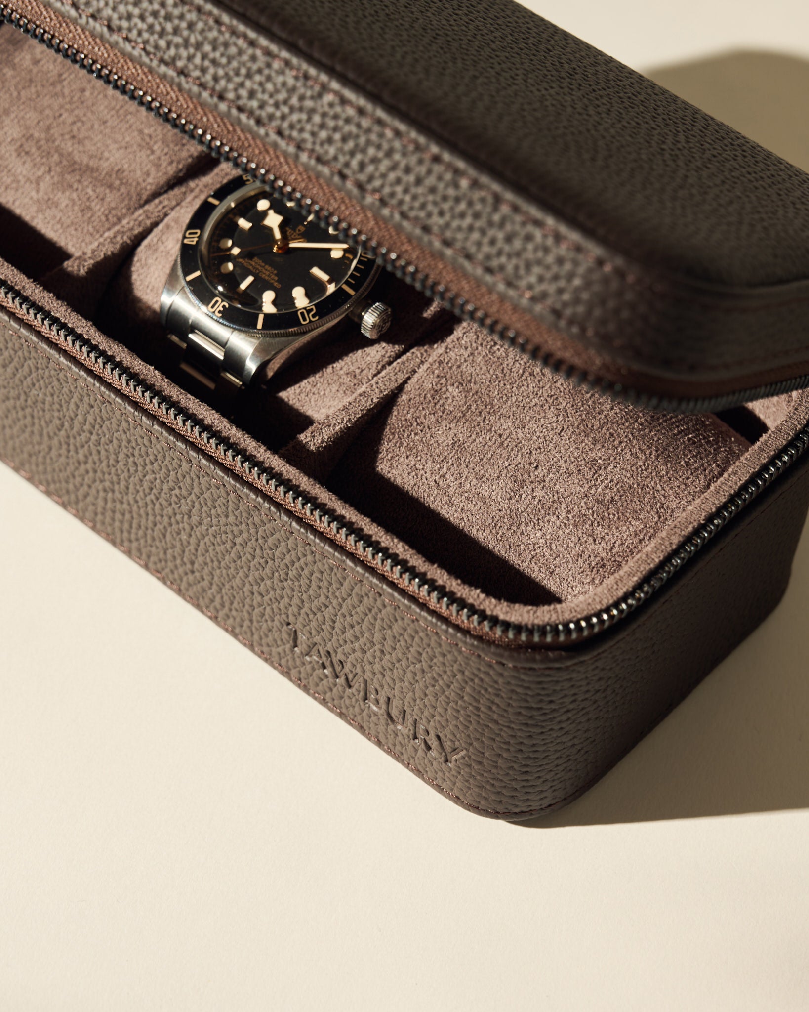 The TAWBURY Fraser 3 Watch Case - Brown features a textured leather exterior and suede interior, ideal for storing your wristwatch with a black bezel and perfect for travel.