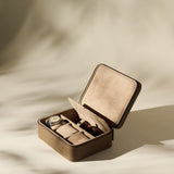 The TAWBURY Fraser 3 Watch Case with Storage in taupe features a textured leather finish, a hinged lid, and compartments for organizing watches and sunglasses, displayed against a neutral background.