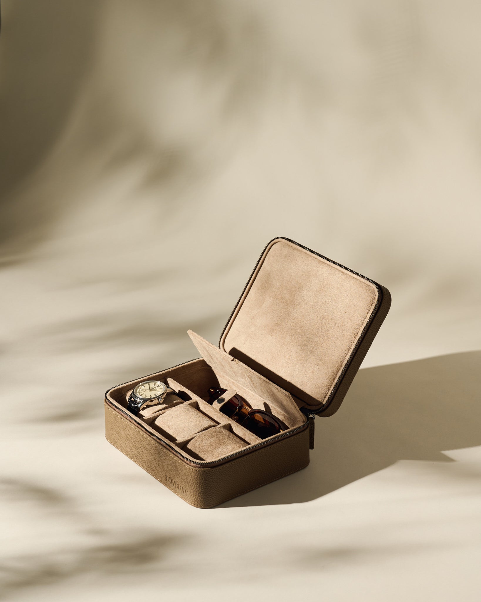 The TAWBURY Fraser 3 Watch Case with Storage in taupe features a textured leather finish, a hinged lid, and compartments for organizing watches and sunglasses, displayed against a neutral background.