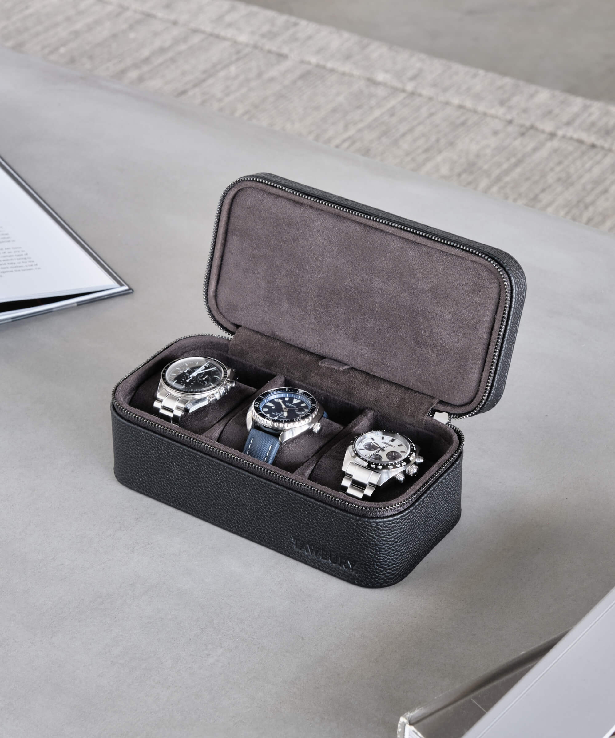 Three TAWBURY Fraser 3 Watch Travel Cases - Black in a navy blue leather case on a desk.