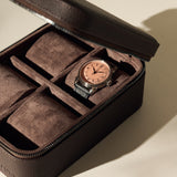 The TAWBURY Fraser 4 Watch Case - Brown features a zippered lid and four compartments, shown here storing a single wristwatch with a black band and rose gold face.