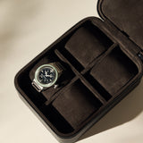 A TAWBURY Fraser 4 Watch Case - Black holds a wristwatch with a metal band, while its other three compartments are empty.