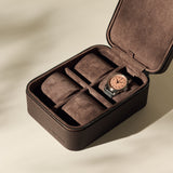 The TAWBURY Fraser 4 Watch Case - Brown features leather construction, a suede interior, and storage for four watches; one wristwatch with a copper face is stored inside, leaving three compartments free—perfect for stylish travel.