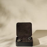 The TAWBURY Fraser 6 Watch Case in black leather with a suede interior is shown open on a neutral background, displaying two wristwatches inside amid soft shadows.