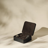 The Fraser 6 Watch Case by TAWBURY, in black leather with a soft interior, securely holds six wristwatches and is shown on a neutral background with gentle shadows.