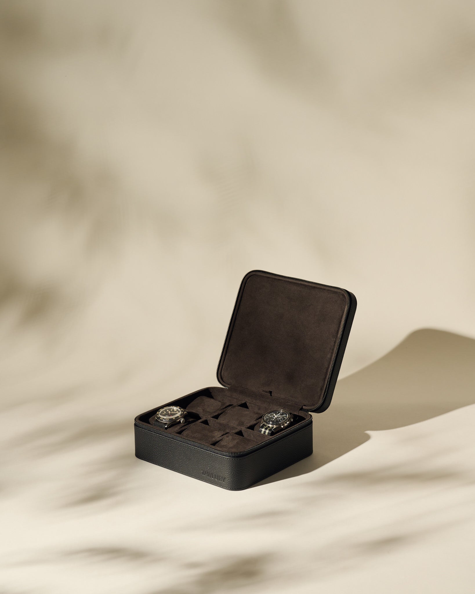 The Fraser 6 Watch Case by TAWBURY, in black leather with a soft interior, securely holds six wristwatches and is shown on a neutral background with gentle shadows.