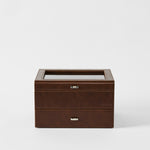 The TAWBURY Bayswater 6 Watch Jewelry Box in chestnut brown faux leather features a glass top and two drawers, elegantly displayed against a plain white background.