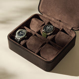 Two wristwatches are displayed in the TAWBURY Fraser 6 Watch Case - Brown, with several empty compartments, set on a light-colored surface.