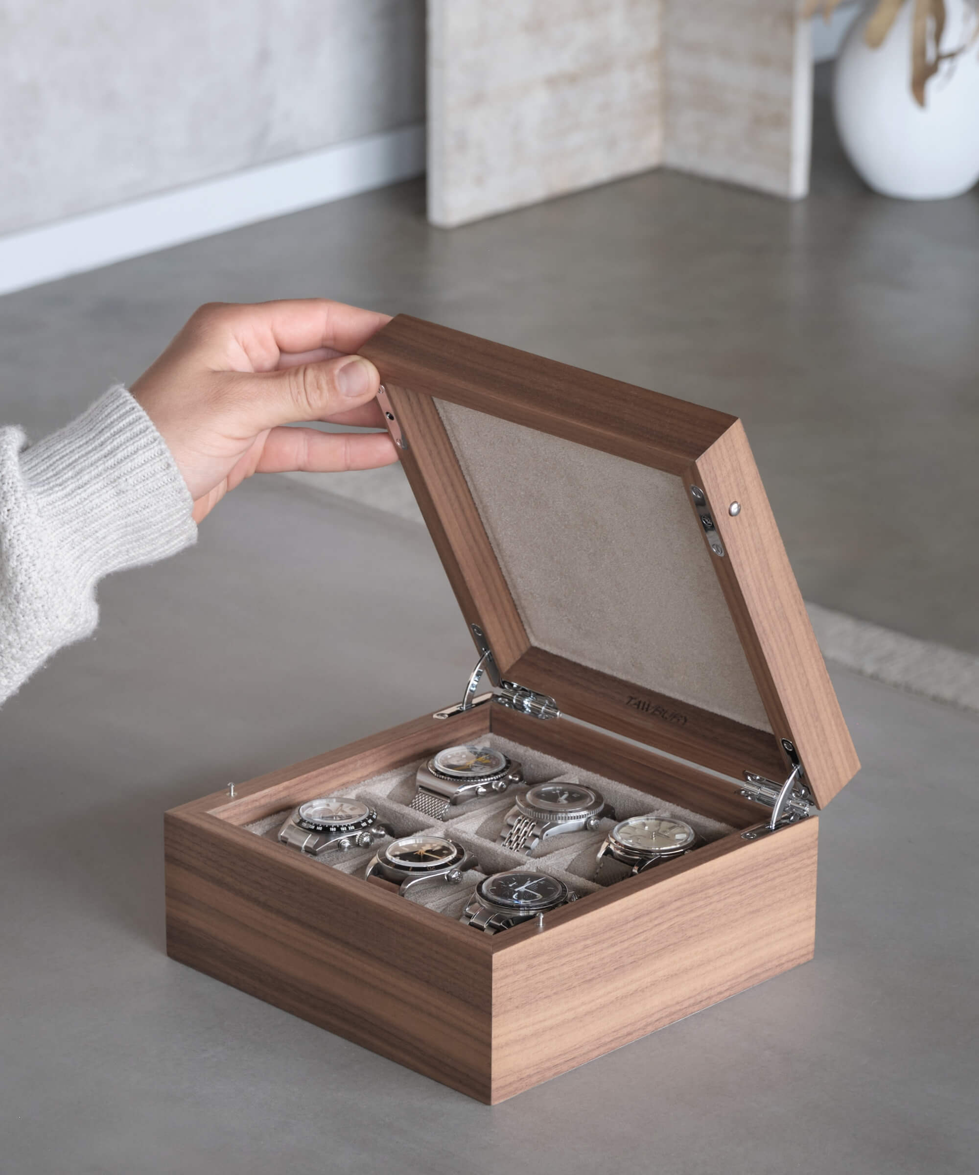 A watch enthusiast holding a TAWBURY Grove 6 Slot Watch Box with Solid Lid - Walnut, designed to organize and protect watches while also displaying them.