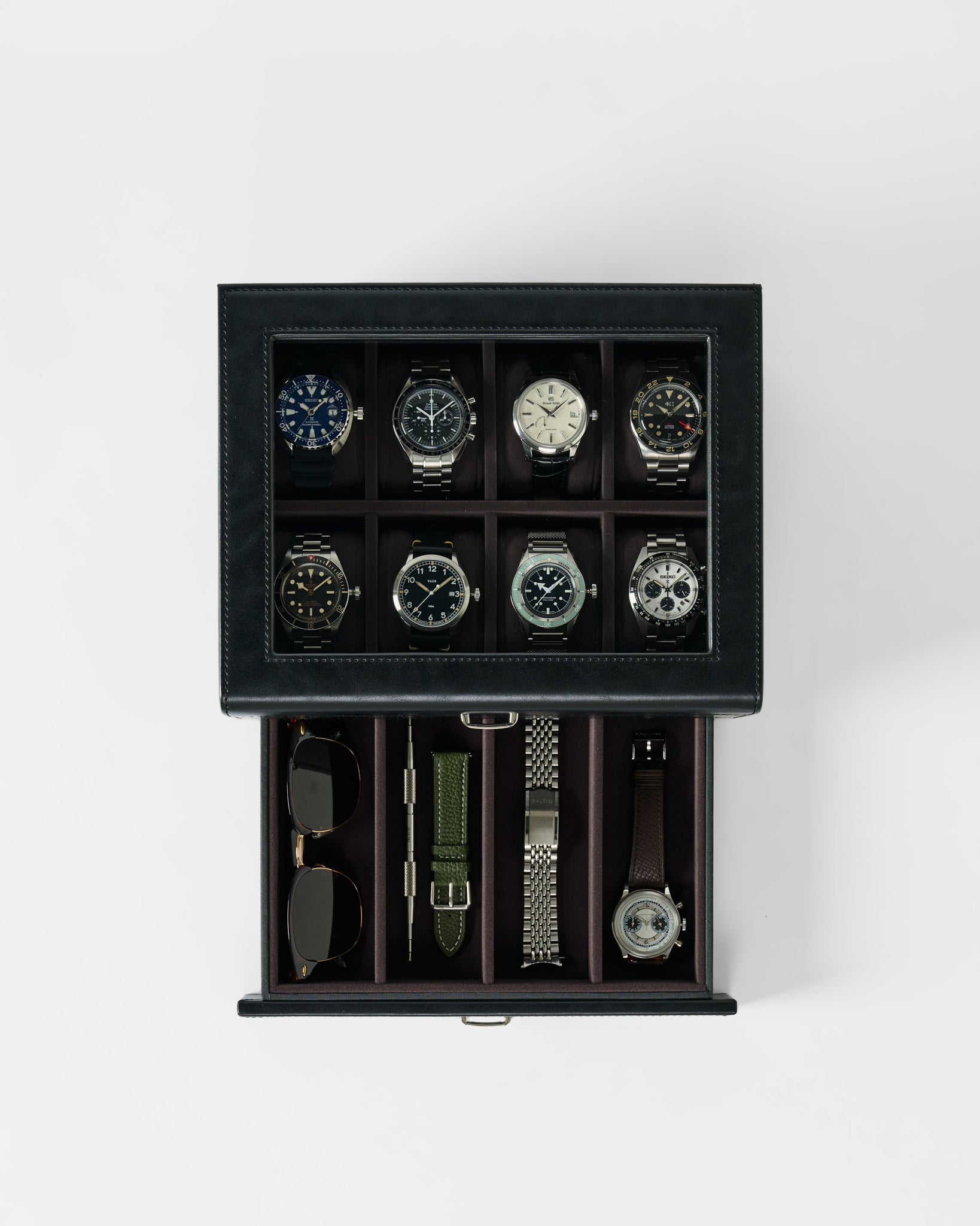 The TAWBURY Bayswater 8 Slot Watch Box with Storage in Black/Charcoal stylishly displays eight watches under a glass top and features a lower drawer for storing sunglasses, straps, and an additional watch.