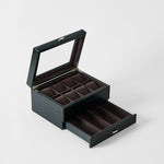 The TAWBURY Bayswater 8 Slot Watch Box with Storage in Midnight Black features a glass lid, multiple velvet-lined compartments, and an open drawer beneath, all elegantly finished for stylish watch organization.