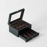 The TAWBURY Bayswater 8 Slot Watch Box with Storage in Midnight Black features a glass lid, multiple velvet-lined compartments, and an open drawer beneath, all elegantly finished for stylish watch organization.