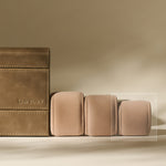 A TAWBURY Bayswater 8 Slot Watch Box in brown leather sits beside three beige Bayswater Watch Pillows (Beige, 55mm, X-Small) on a neutral background.