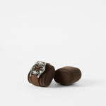 A TAWBURY Bayswater Watch Pillow in Graphite (50mm, X-Small) with a brown-strap wristwatch rests on a plain white background next to an empty matching cushion, both showcasing stylish Bayswater accessories.