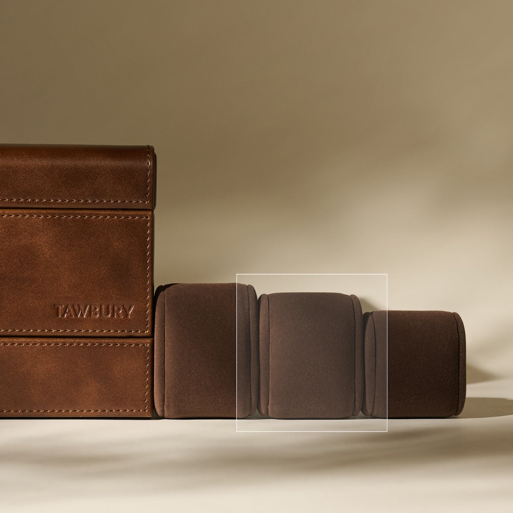 Three brown/grey TAWBURY Bayswater Watch Pillows (Small, 55mm) are placed side by side on a beige surface; "TAWBURY" is embossed on the largest pillow.