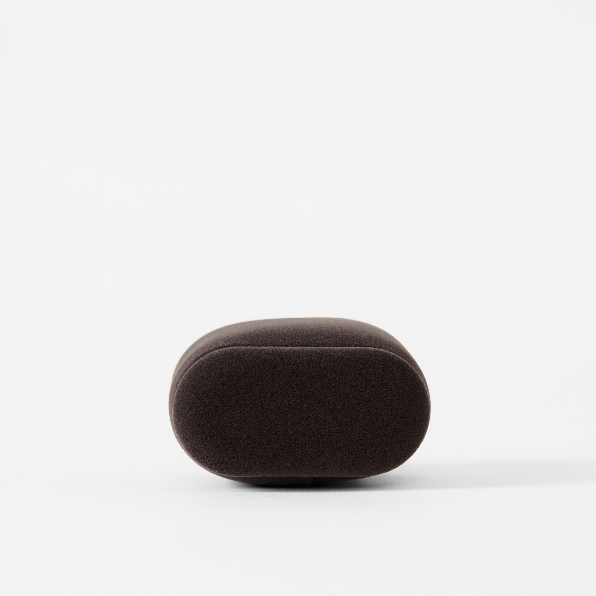 A small, dark charcoal, oval-shaped Bayswater Watch Pillow by TAWBURY (55mm), with a smooth surface, is placed on a plain white background.