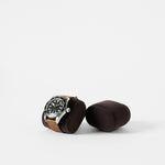A wristwatch with a brown leather strap rests on a dark cushion, similar to TAWBURY's Bayswater Watch Pillows – Charcoal, 55mm, X-Small, displayed beside an empty matching pillow against a plain white background.