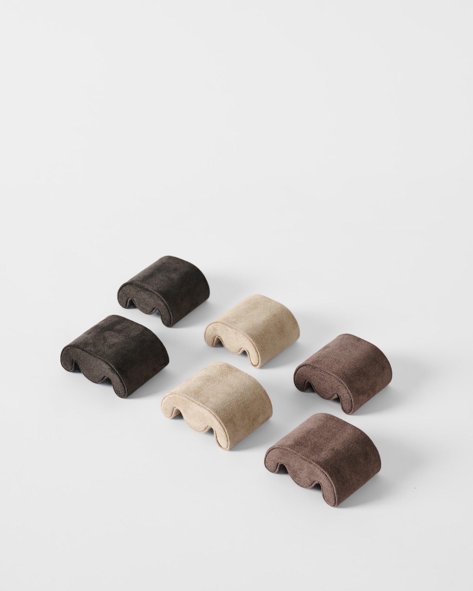 Six plush, curved pillows in dark brown, beige, and light brown are arranged in two rows on white—ideal for displaying or placing inside your TAWBURY Fraser 3 Watch Case - Brown for stylish travel or storage.