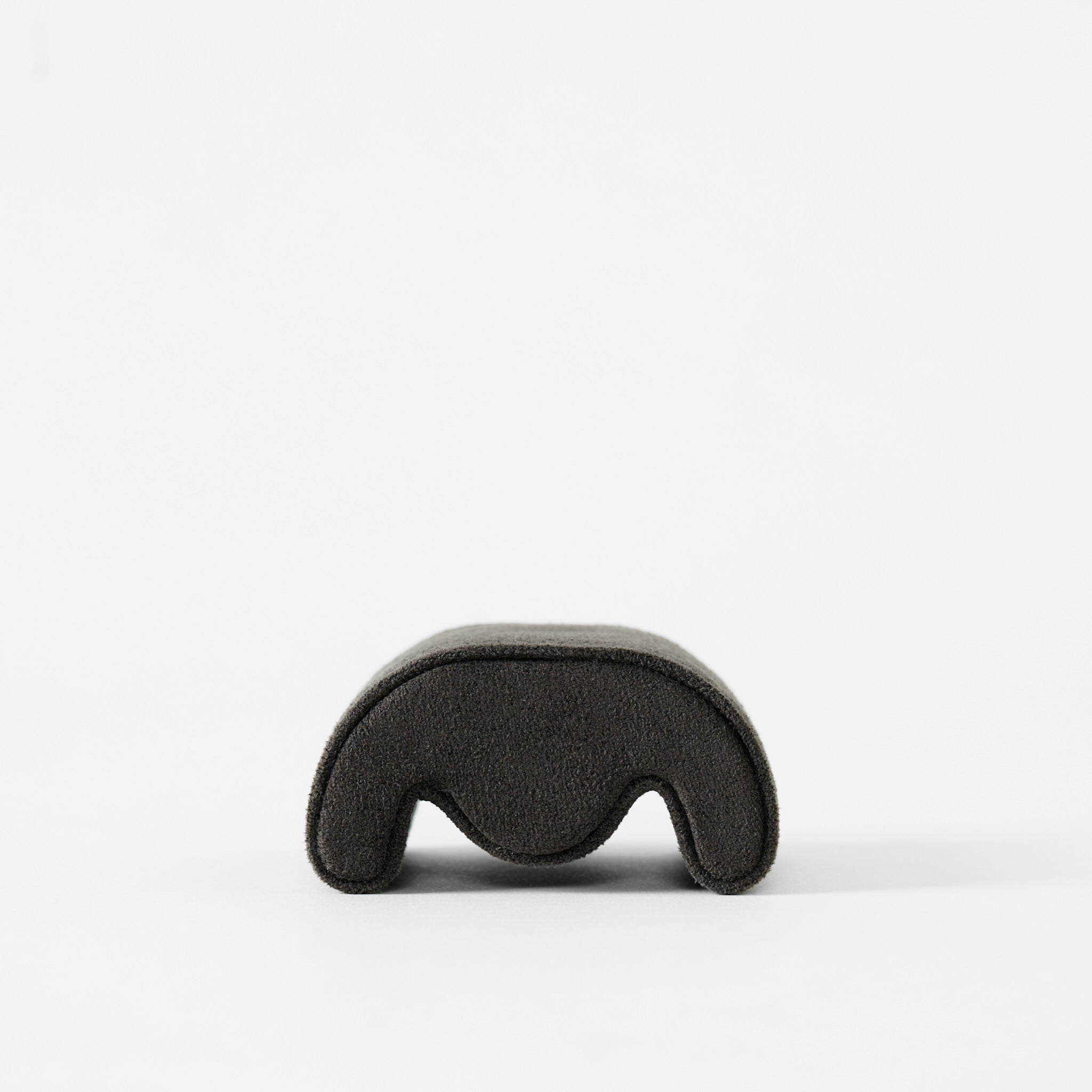 A Fraser Watch Pillow - X-Small by TAWBURY in anthracite, featuring a soft, velvety texture and arch shape, is photographed alone against a plain white background.