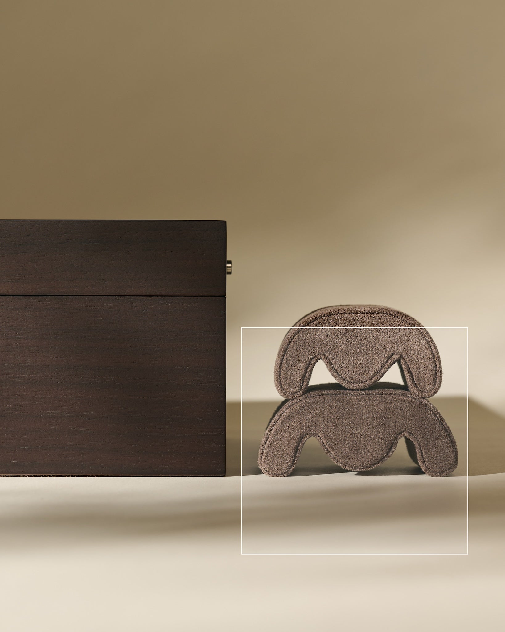 A TAWBURY Grove Watch Pillow in brown sits beside a large brown hair claw clip on a beige surface with a neutral background.