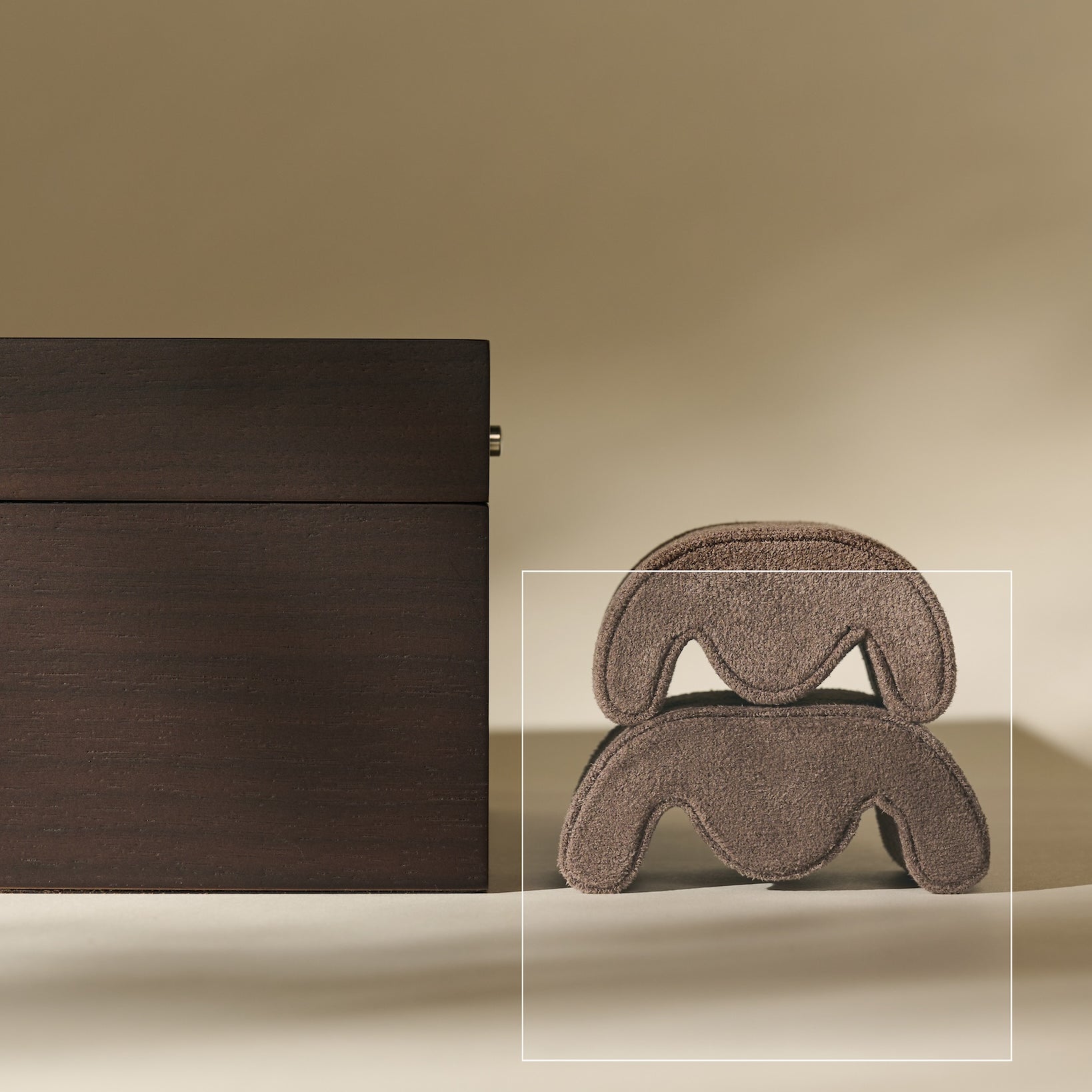A TAWBURY Grove Watch Pillow in brown sits beside a large brown hair claw clip on a beige surface with a neutral background.