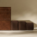 The TAWBURY Bayswater 24 Slot Watch Box with Drawer in Chestnut Brown is shown alongside three brown cushioned watch pillows on a neutral background, highlighting elegant watch storage.