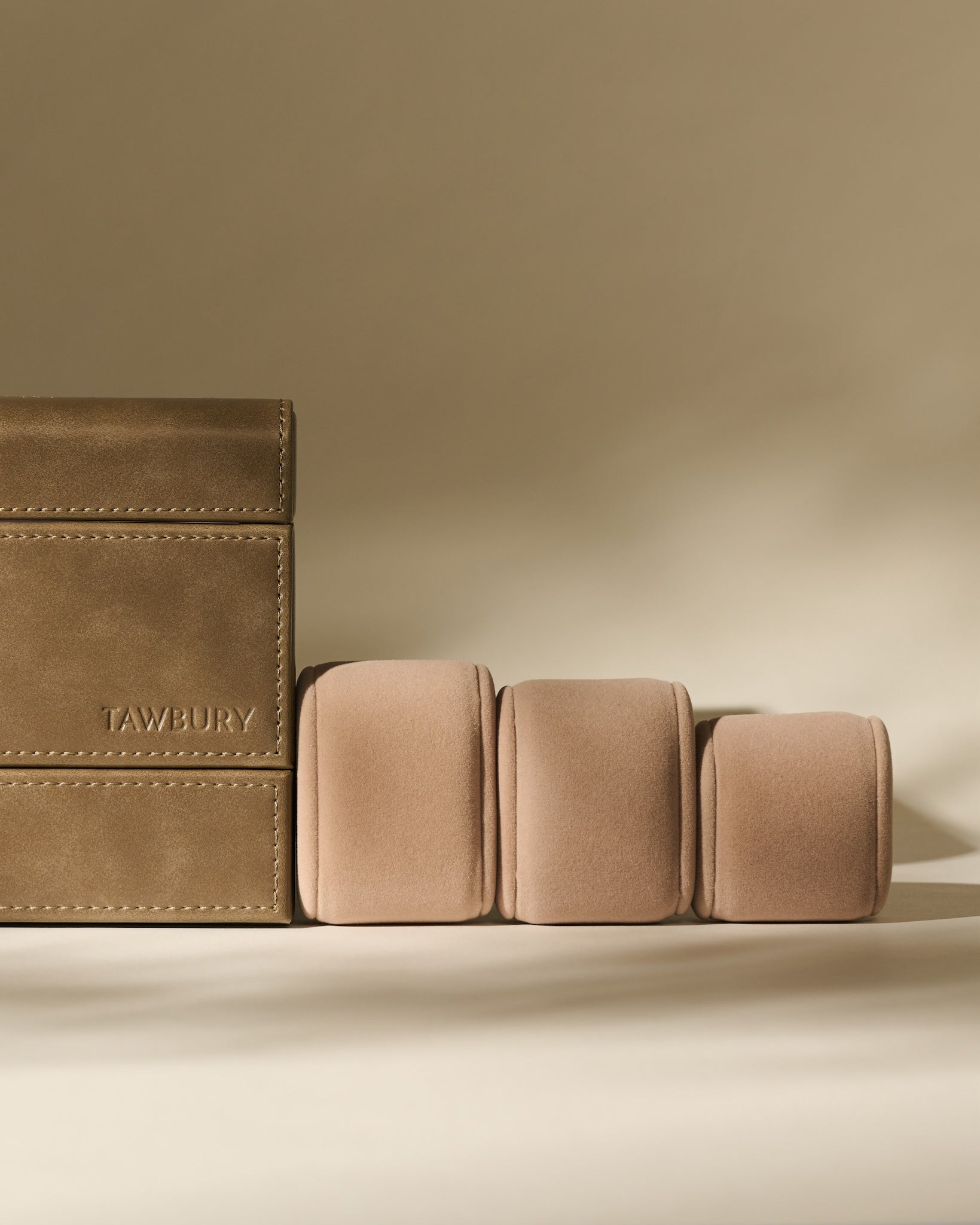 The TAWBURY Bayswater 8 Slot Watch Box with Storage in Driftwood Taupe features elegant faux leather, beige velvet cushions, and refined branding—perfect for stylish watch organization in any setting.