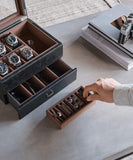 A man is organizing timepieces in a TAWBURY Bayswater 6 Watch Jewellery Box - Black.