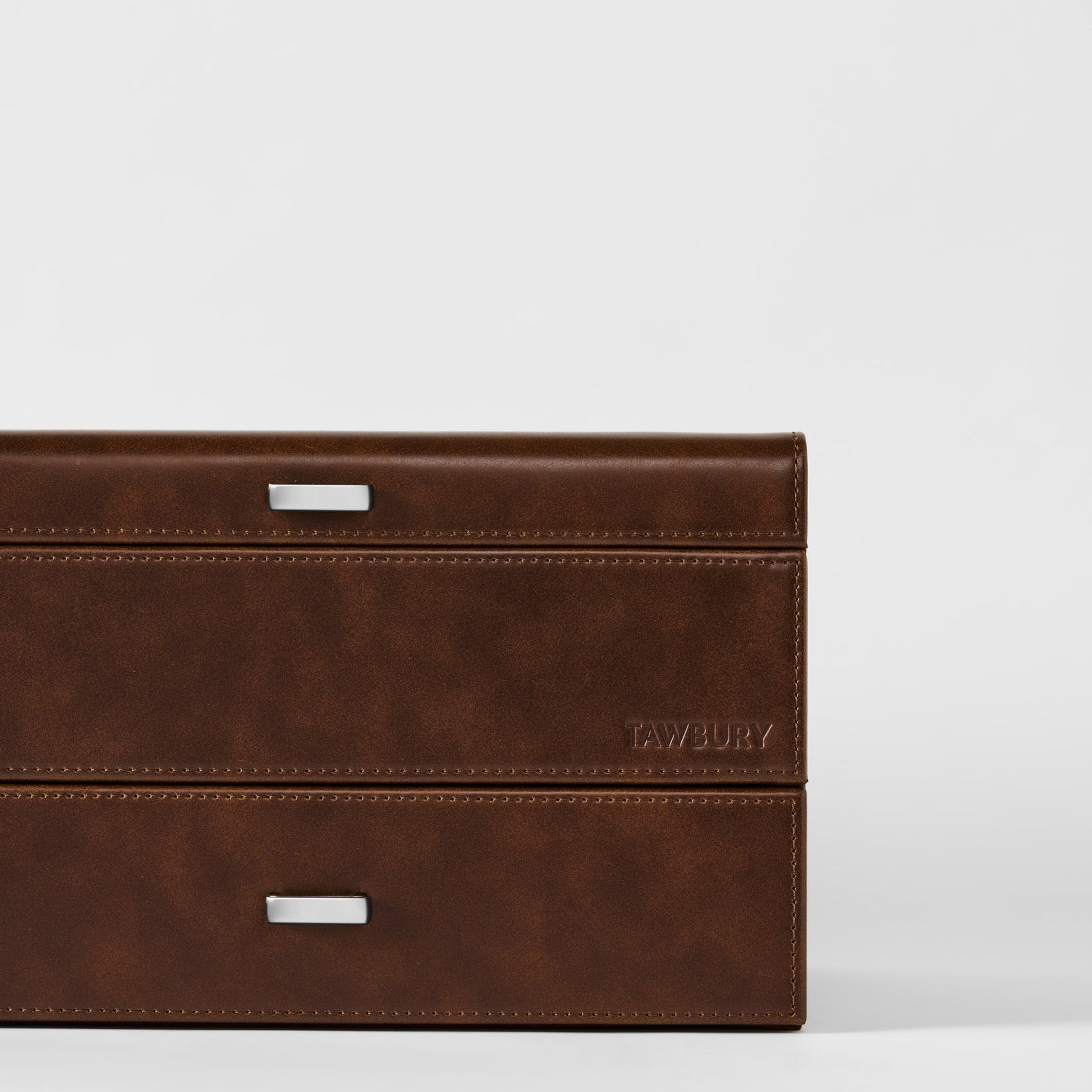 The Bayswater 6 Watch Jewelry Box by TAWBURY features brown leather, two silver handles, and "TAWBURY" embossed on the lower right side, set against a plain white background.
