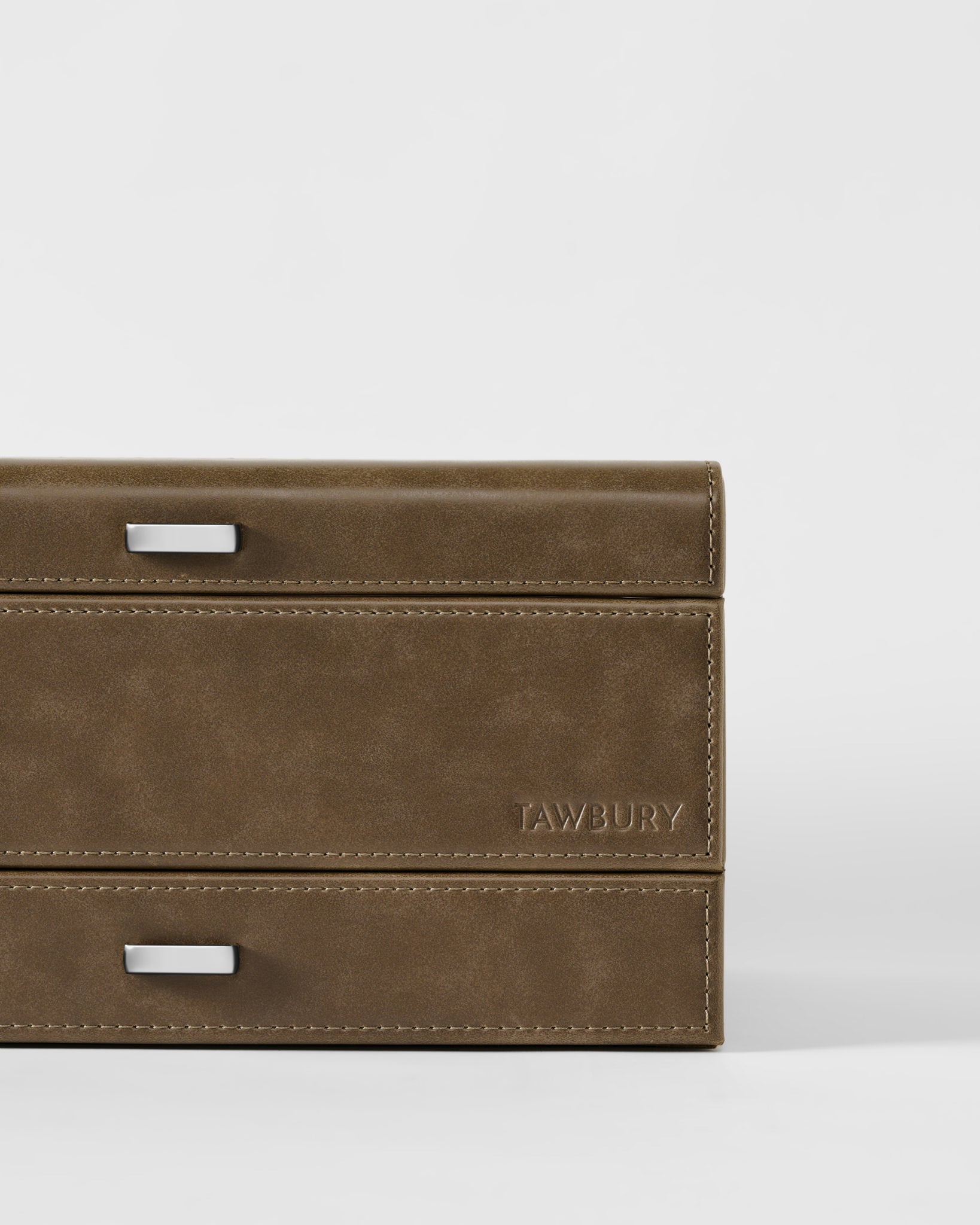 Close-up of the TAWBURY Bayswater 8 Slot Watch Box in taupe, featuring visible stitching, two metal handles, and "TAWBURY" embossed on the lower right—perfect for elegant watch storage.