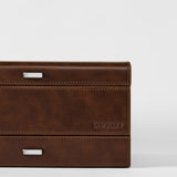 Close-up of the TAWBURY Bayswater 8 Slot Watch Box with Storage in brown faux leather, featuring metal handles and "TAWBURY" embossed on the lower right corner, set against a plain white background.