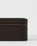 A close-up of the Fraser 3 Watch Case by TAWBURY shows its textured dark brown leather and embossed branding, perfect for stylishly storing your watches while traveling.