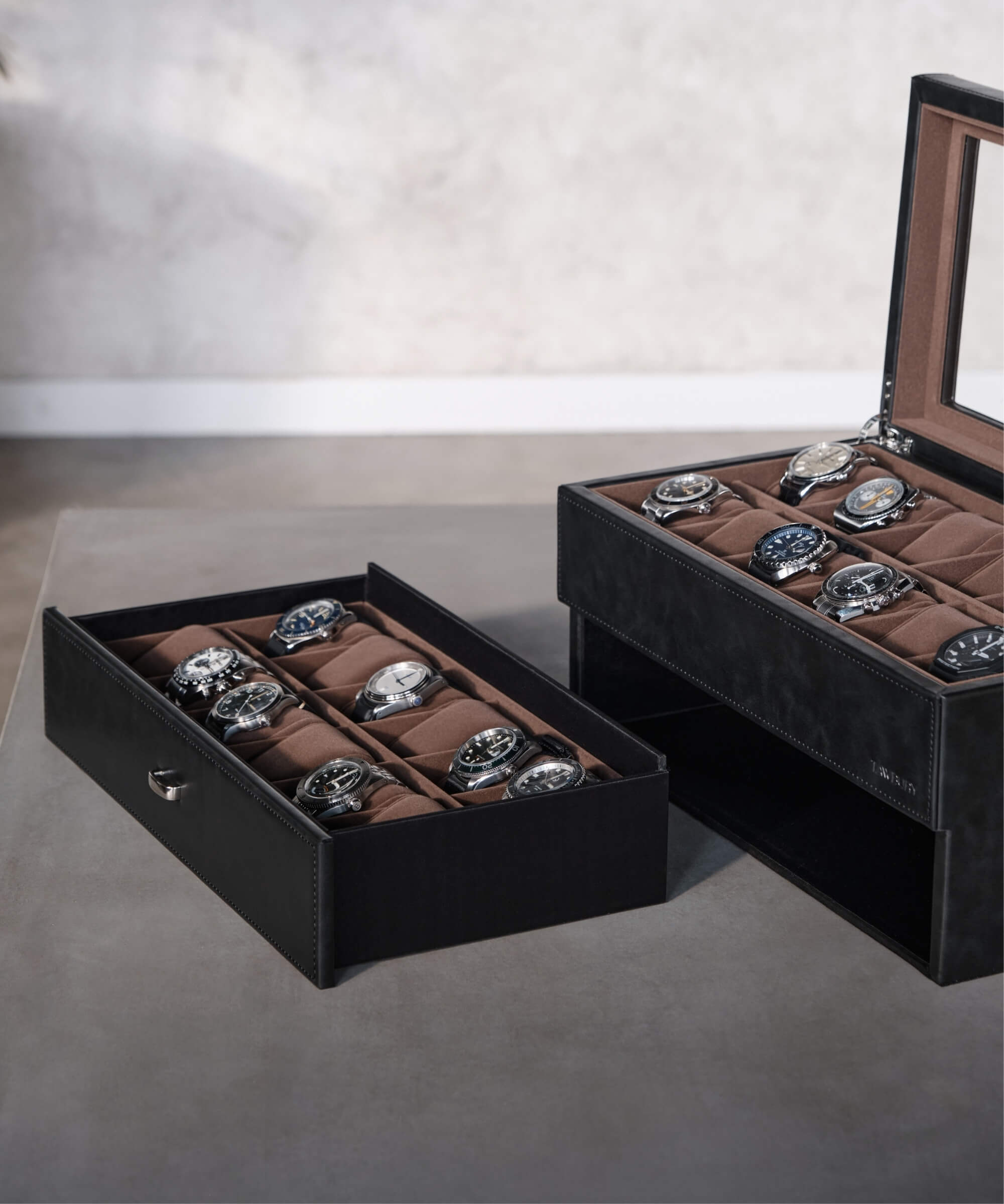A TAWBURY Bayswater 24 Slot Watch Box with Drawer - Black that organizes several timepieces.