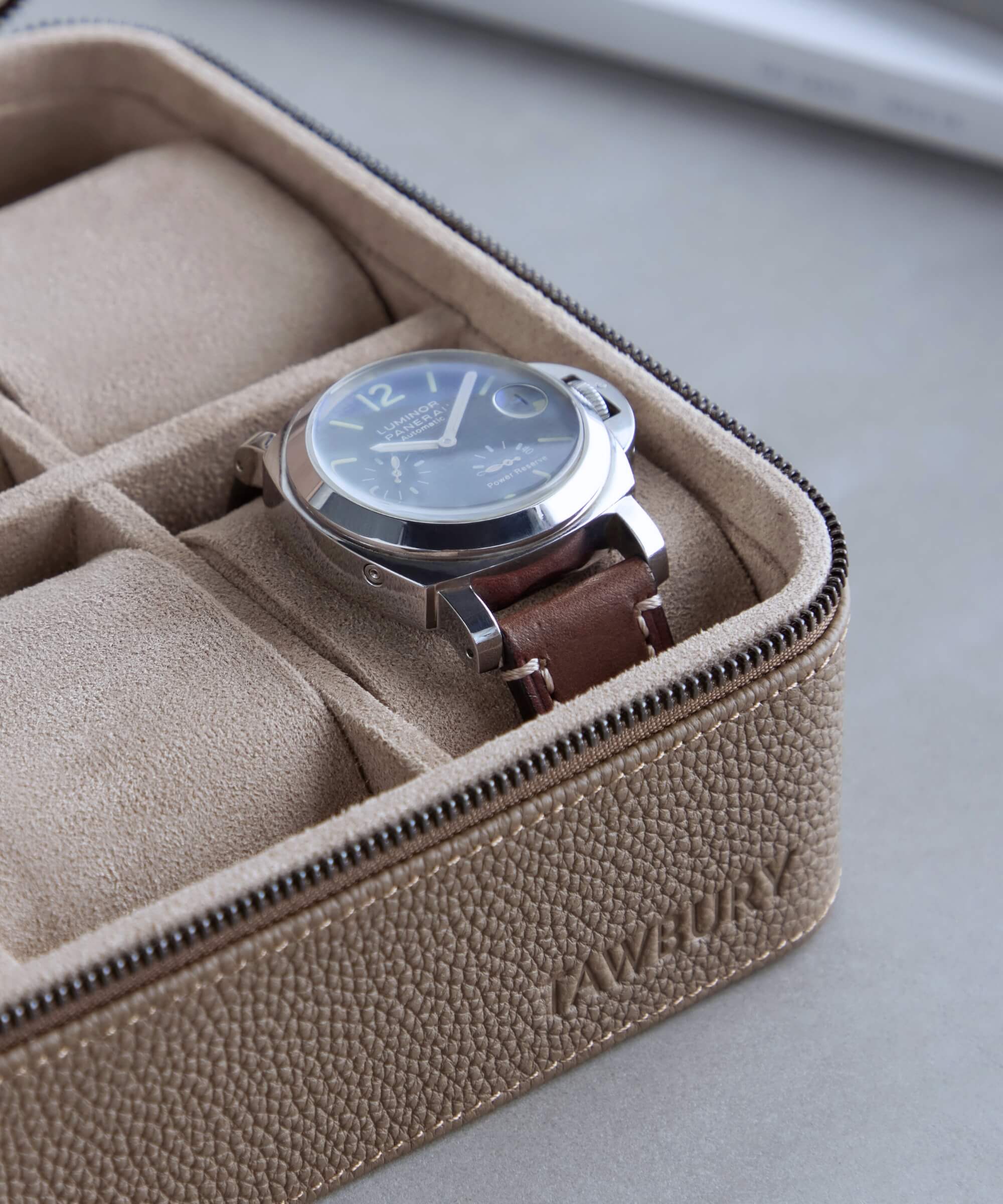 A silver wristwatch with a brown leather band placed in a Fraser 4 Watch Travel Case - Taupe (Coming Soon), showing two additional empty slots. The case is branded "TAWBURY" and is part of the TAWBURY range.