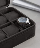 A black watch with a leather strap, elegantly stored in the luxury leather Fraser 6 Watch Travel Case - Black (Coming Soon) from the TAWBURY range.