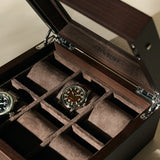 The TAWBURY Grove 6 Slot Wooden Watch Box in dark walnut features a glass lid and multiple suede-lined compartments, stylishly organizing and displaying your timepieces, with two watches shown separately.