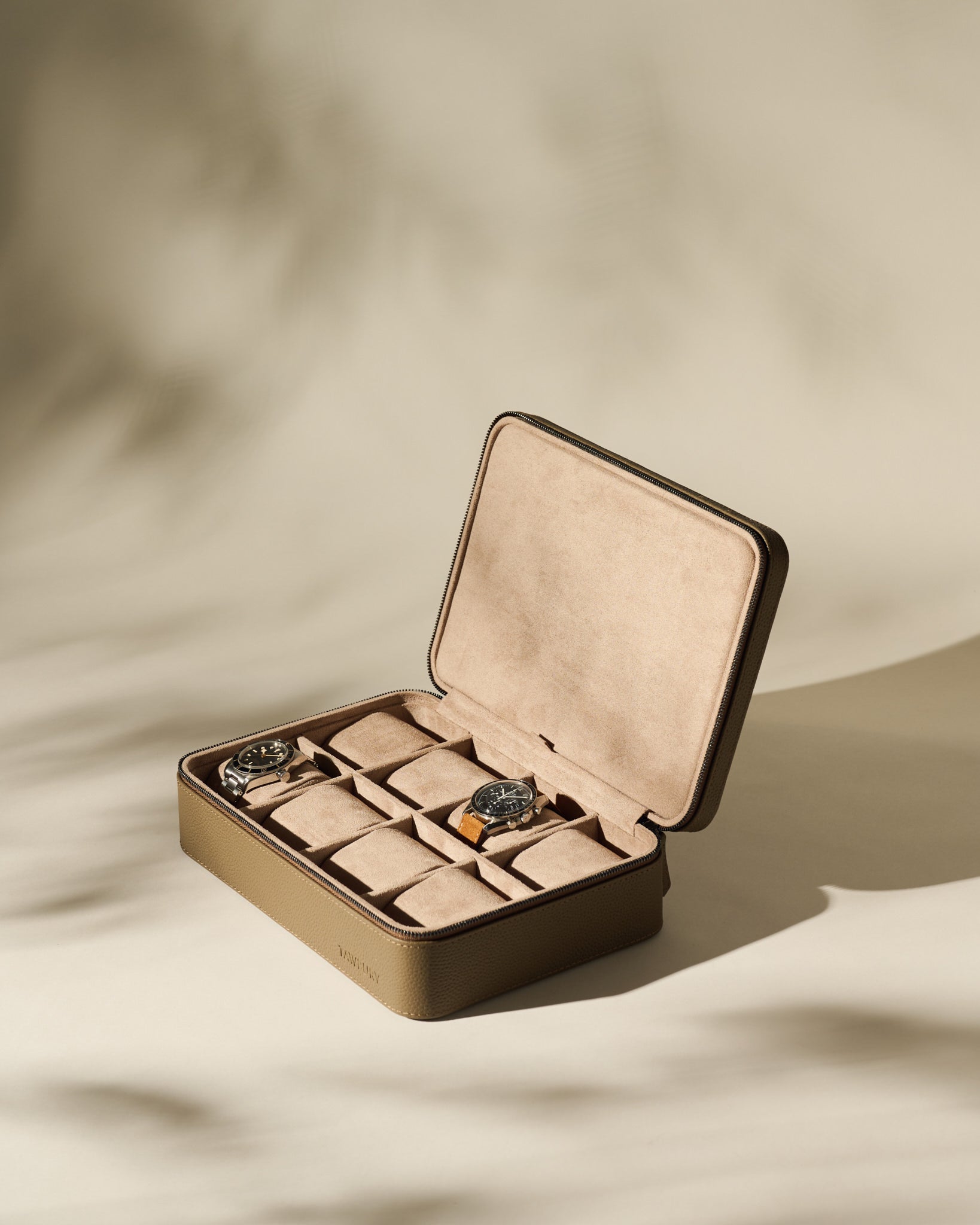 The TAWBURY Fraser 8 Watch Case in taupe leather is shown open, displaying two wristwatches and multiple empty compartments against a neutral background.