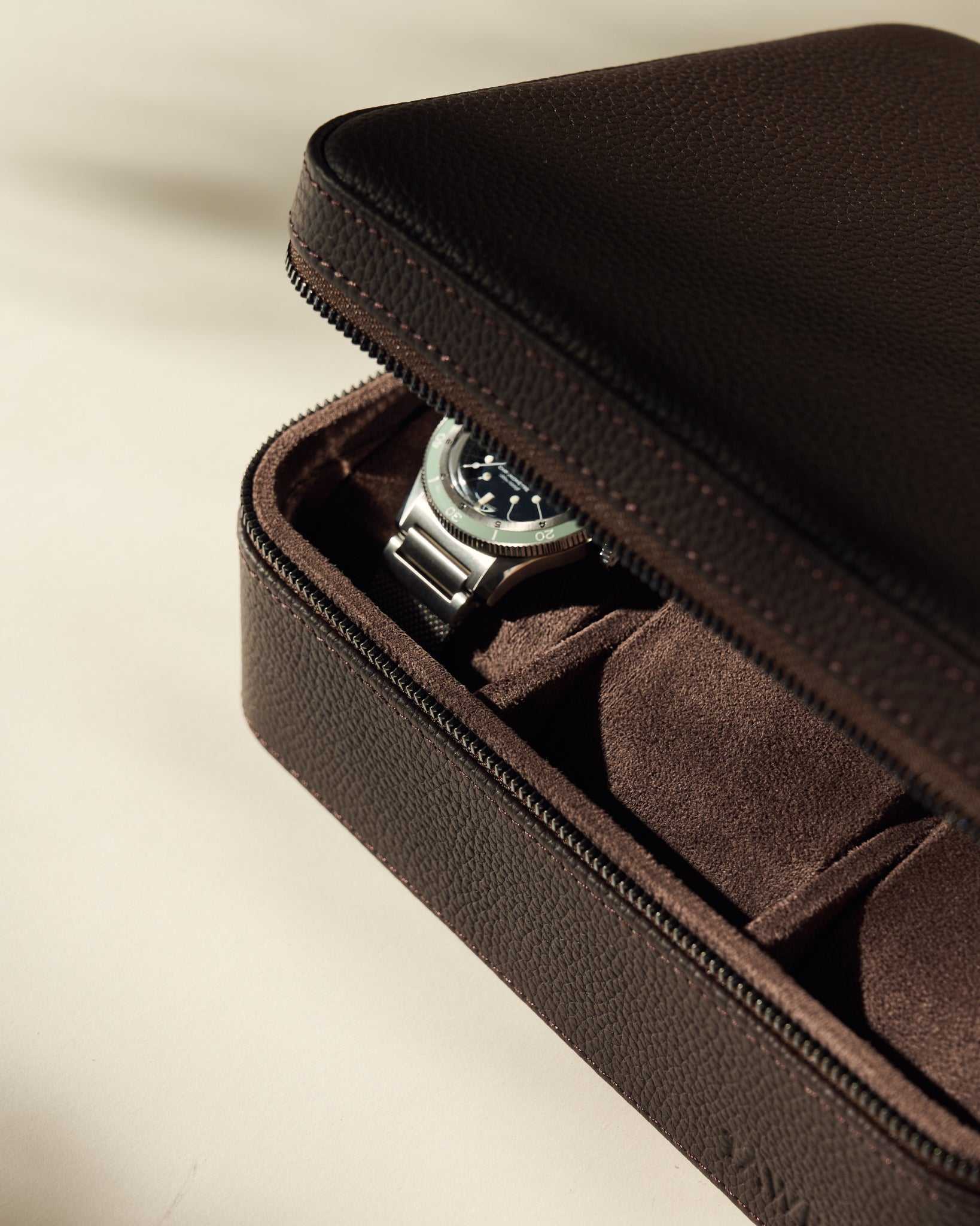 The TAWBURY Fraser 6 Watch Case in brown leather features a zipper for secure closure and stylishly protects your wristwatch collection with elegance and ease.
